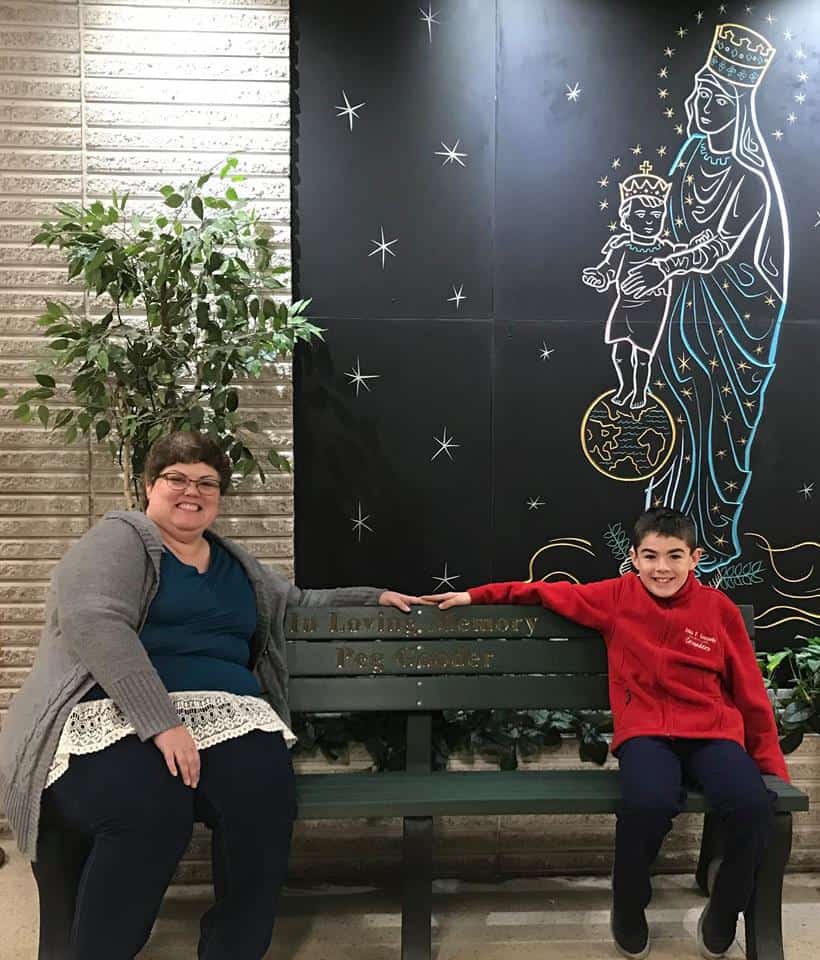 JFK Catholic School students sitting on a bench indoors.