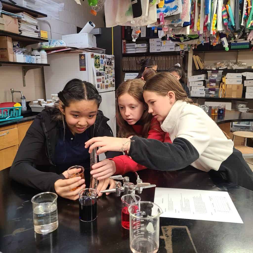 Students conducting a science experiment in JFK Catholic School classroom.