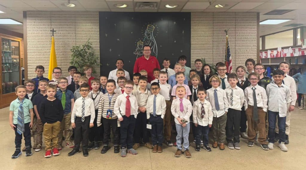 First Communion boys in shirts and ties standing with the principal.