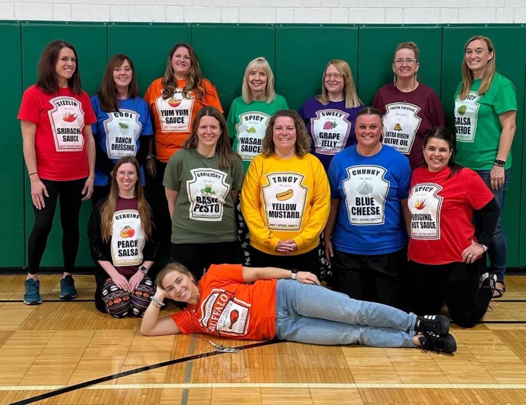 Group of teachers wearing colorful T-shirts with food labels at JFK Catholic School.