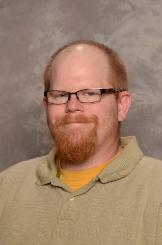 Portrait of Matt Ryan, art teacher at JFK Catholic School, smiling with glasses.