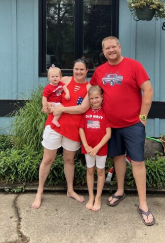Family with children at JFK Catholic School preschool, smiling outdoors.