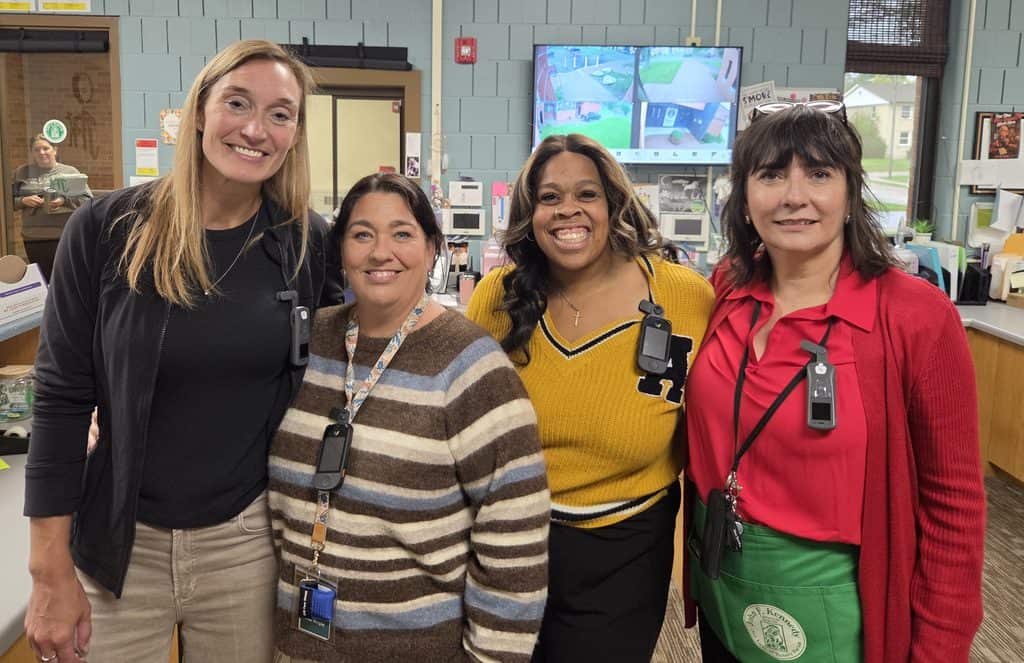 School staff members smiling in classroom at JFK Catholic School.